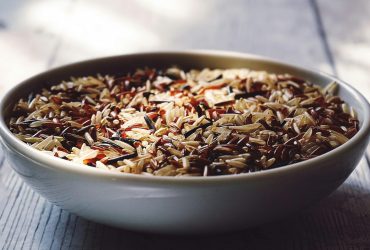 Close-up view of a bowl filled with mixed wild and brown rice grains.